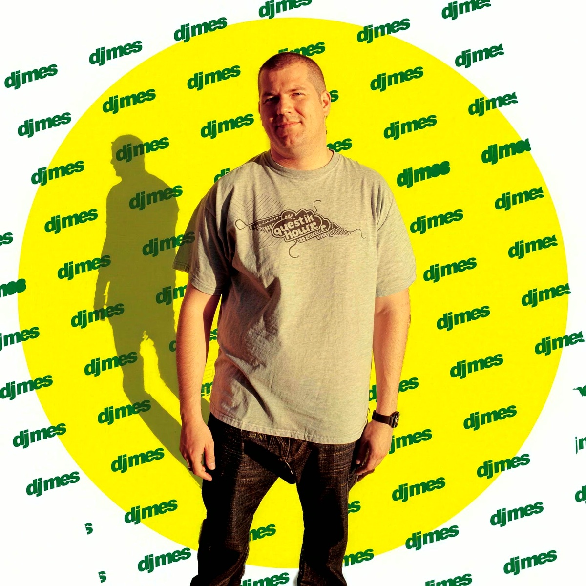 DJ Mes standing in front of a yellow circle covered in the djmes logo